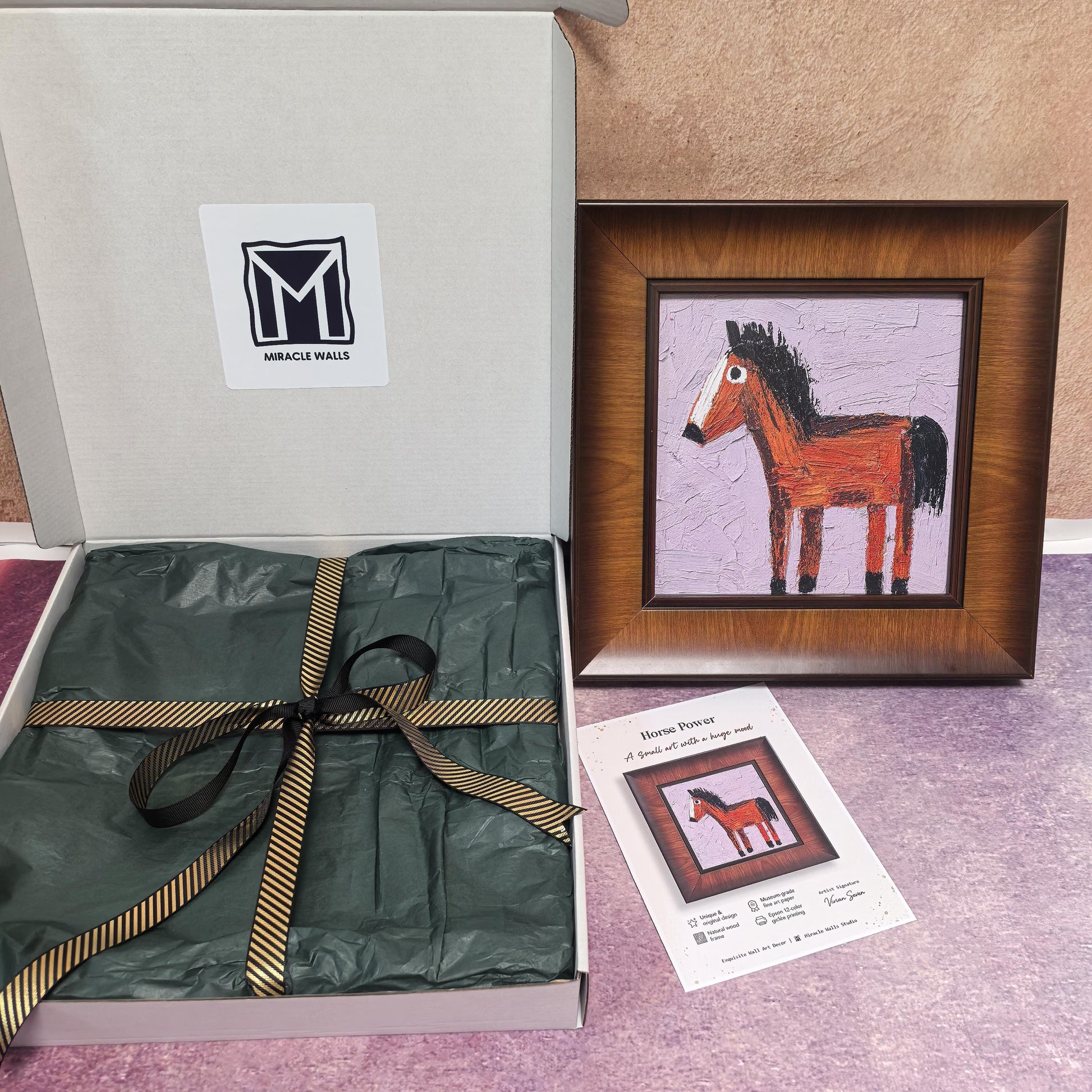 An unboxing display of the "Horse Power" art piece next to its "Miracle Walls" branded shipping box. The box is elegantly lined with dark green tissue paper and tied with a gold-striped black ribbon.