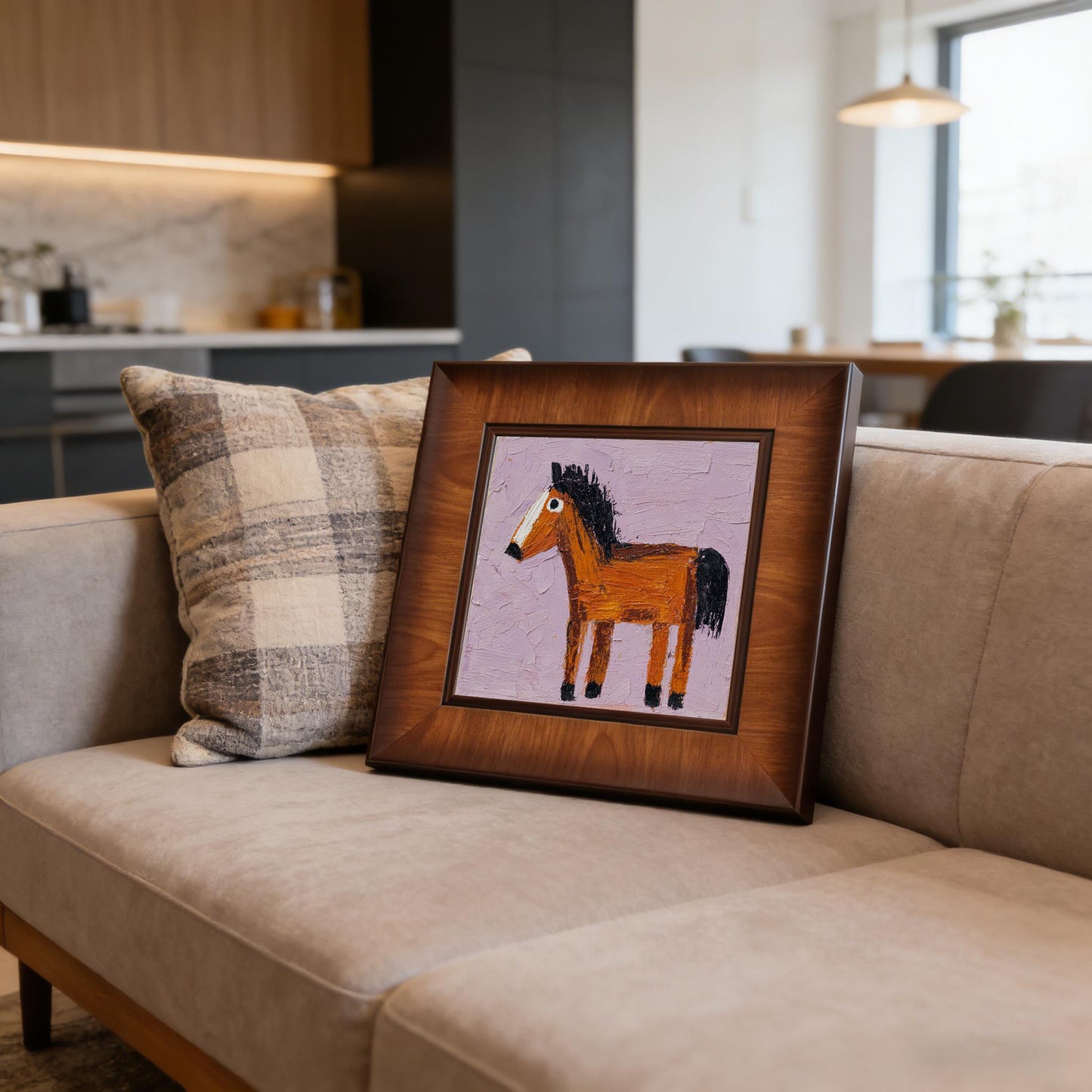 Naive-style horse art print in a square wooden frame resting on a light grey sofa next to a plaid pillow in a modern living room.