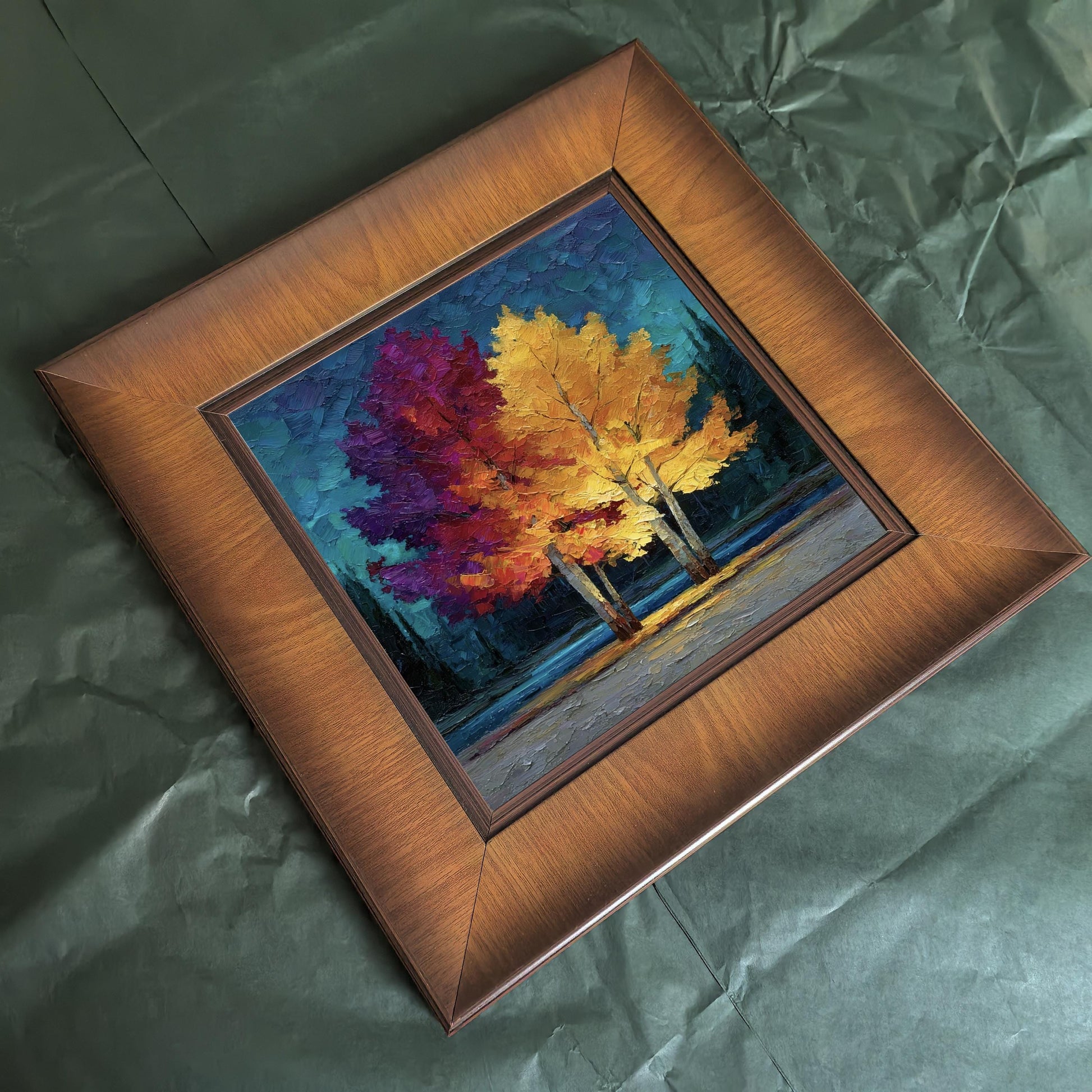 Overhead flat lay of the square wood-framed painting resting on dark green tissue paper, perfect for showing packaging or gift-ready quality.