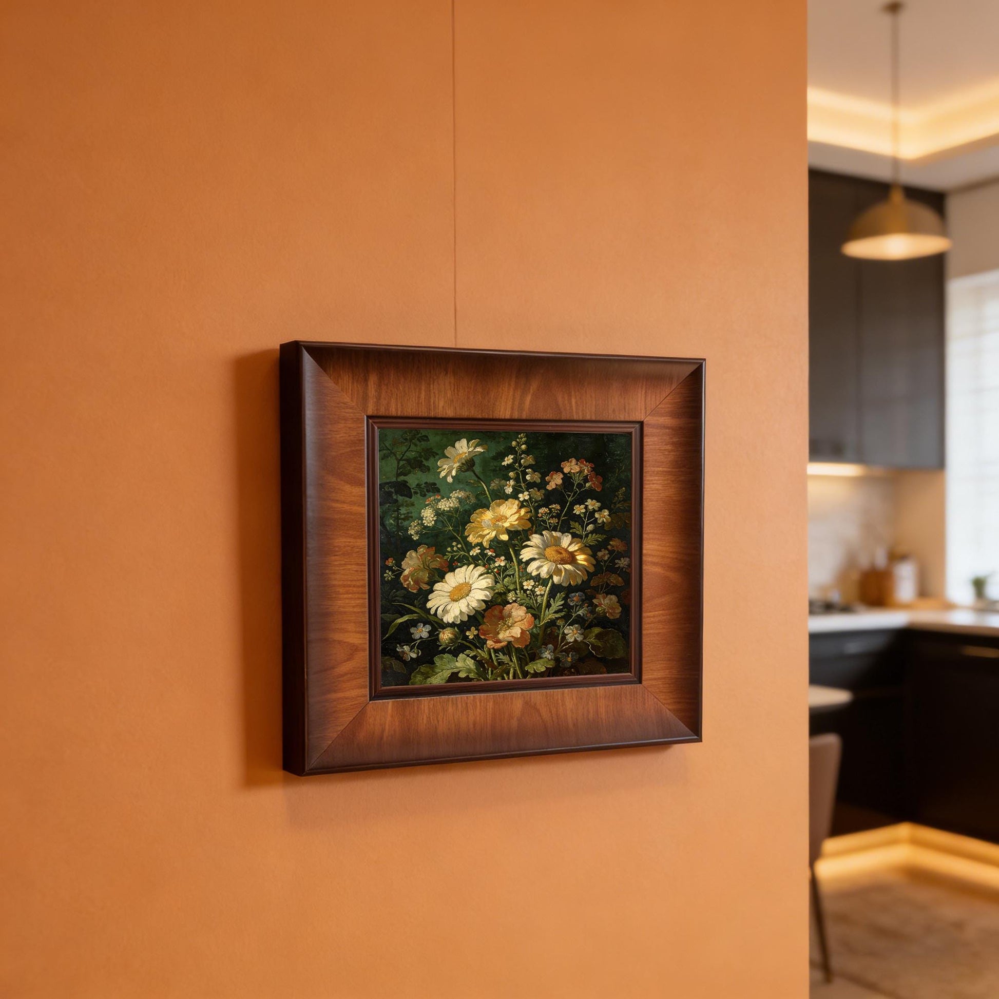 Square framed botanical wall art featuring daisies and wildflowers, hung on a warm terracotta-colored wall in a modern kitchen setting.