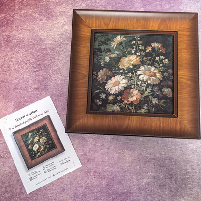 A direct, front-facing view of the "Secret Garden" framed art. The square print features a lush, vintage-style floral arrangement with white daisies and warm-toned wildflowers against a dark, moody background, all set in a wide, dark wood frame.